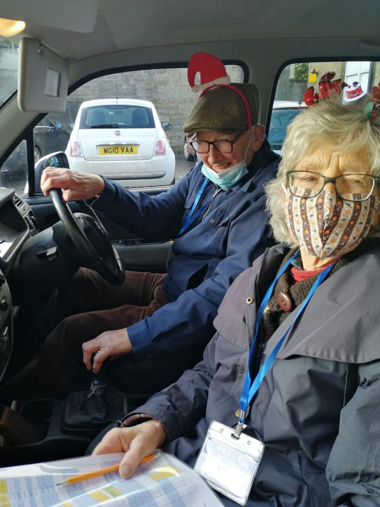 Husband and wife volunteers in car wearing masks